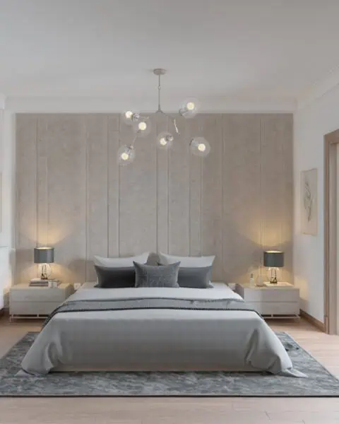 Modern, neutral-toned bedroom with a low bed, gray bedding, and matching nightstands flanking a padded panel headboard.