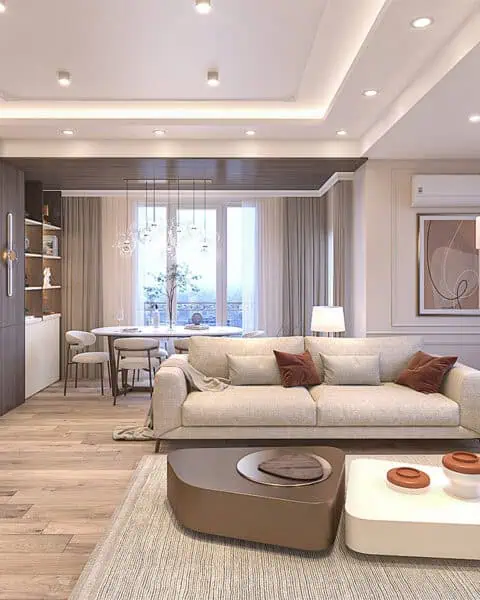 Küçükyalı salon tasarımı içinde açık renk koltuklar, yemek masası, özel kitaplık ve sıcak aydınlatma