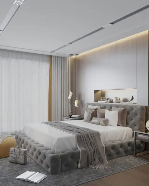 Luxurious gray tufted bed with white bedding in a modern bedroom with built-in shelves and warm accent lighting